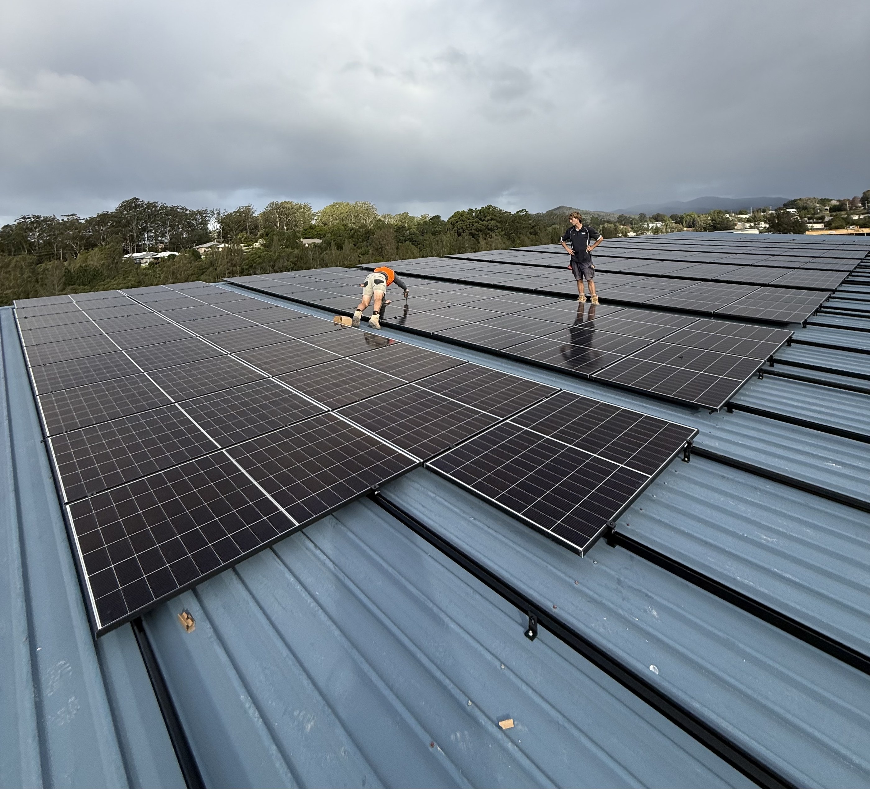 Two Coffs Coast Electrical installers laying panels on the Mid Coast Trucks roof