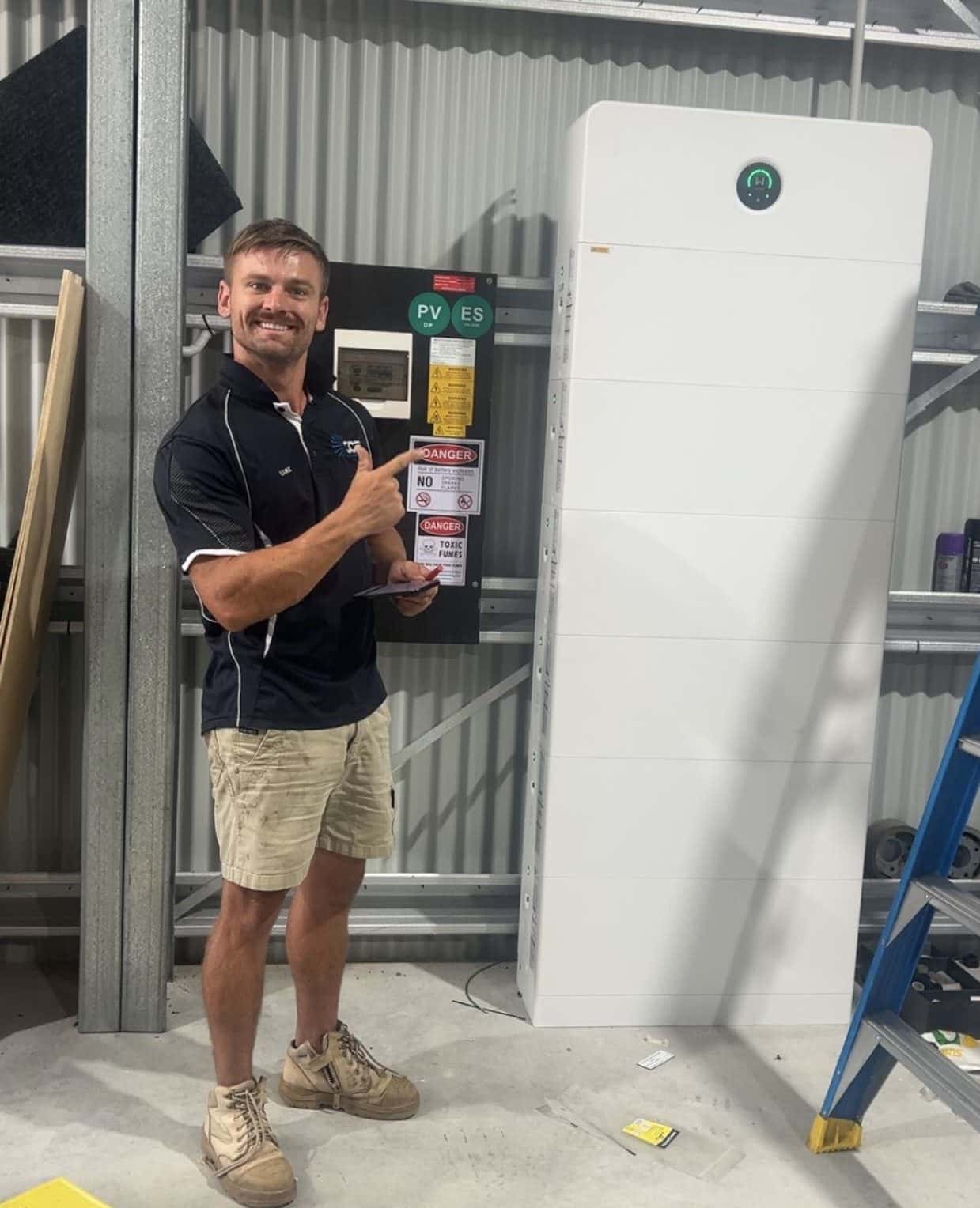 Luke beside a stacked GoodWe battery and its switchboard in a shed at Bonville