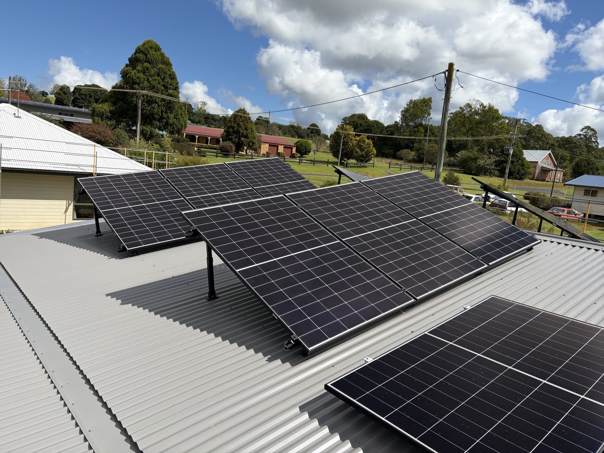 Panels on tilt frames across a light-grey iron roof in Dorrigo village