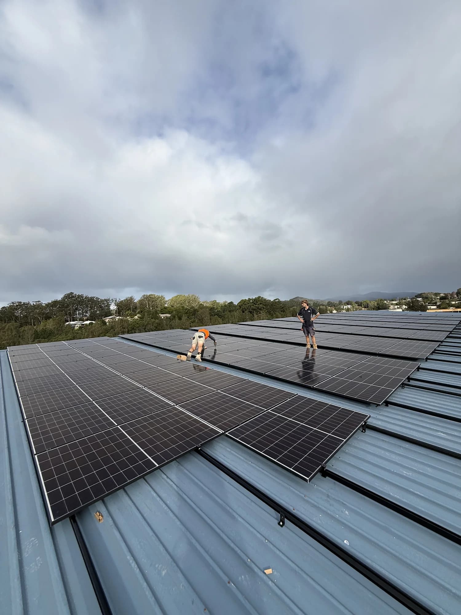 Two installers laying panels on rails on the Mid Coast Trucks roof